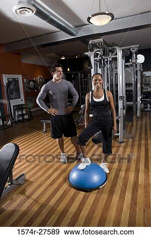 Trainer standing by a young woman in the gym View Large Photo Image Stock Photo - Trainer standing by a young woman in the gym. Fotosearch