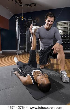 Trainer stretching leg of a young woman in the gym View Large Photo Image Picture - Trainer stretching leg of a young woman in the gym. Fotosearch
