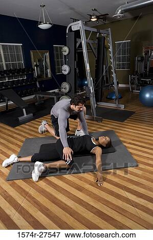 Trainer stretching leg of a young woman in the gym View Large Photo Image Stock Photo - Trainer stretching leg of a young woman in the gym. Fotosearch