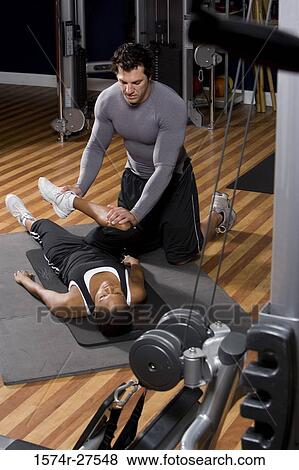Trainer stretching leg of a young woman in the gym View Large Photo Image Stock Photo - Trainer stretching leg of a young woman in the gym. Fotosearch