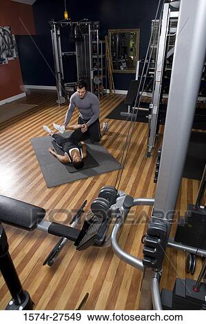Trainer stretching leg of a young woman in the gym View Large Photo Image Stock Photo - Trainer stretching leg of a young woman in the gym. Fotosearch