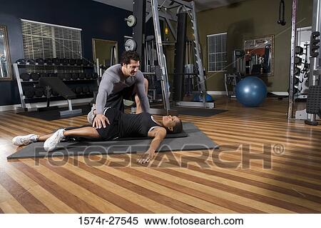 Trainer stretching leg of a young woman in the gym View Large Photo Image Stock Photography - Trainer stretching leg of a young woman in the gym. Fotosearch