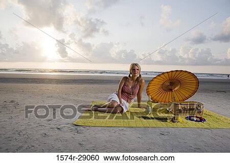 View of a cheerful young woman sitting at the beach View Large Photo Image Stock Image - View of a cheerful young woman sitting at the beach. Fotosearch
