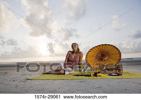 View of a cheerful young woman sitting at the beach View Large Photo Image Stock Image - View of a cheerful young woman sitting at the beach. Fotosearch