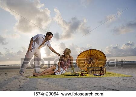 Picture - View of a young couple conversing at the beach. Fotosearch