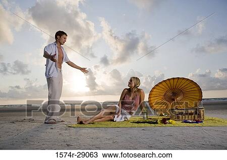 Stock Image - View of a young couple conversing at the beach. Fotosearch