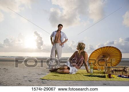 View of a young couple conversing at the beach View Large Photo Image Stock Photo - View of a young couple conversing at the beach. Fotosearch