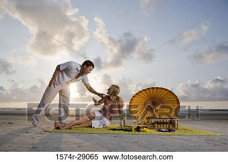 View of a young couple conversing at the beach View Large Photo Image Stock Photography - View of a young couple conversing at the beach. Fotosearch