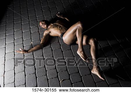 Stock Photography - View of a young man lying on the tiled floor. Fotosearch