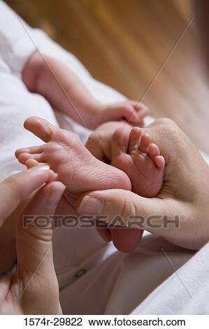 Stock Image - Woman holding her baby's legs. Fotosearch
