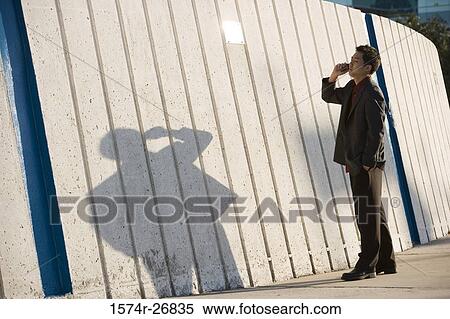 Young businessman using mobile phone by wall View Large Photo Image Stock Photography - Young businessman using mobile phone by wall. Fotosearch