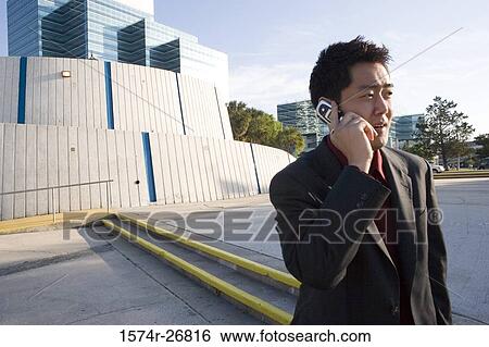 Stock Photograph - Young businessman using mobile phone in front of a building exterior. Fotosearch