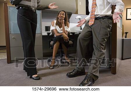 Young businesswoman looking at colleagues discussing View Large Photo Image Stock Photograph - Young businesswoman looking at colleagues discussing. Fotosearch