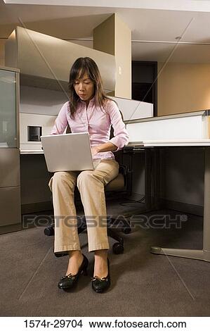 Picture - Young businesswoman working on laptop in an office. Fotosearch