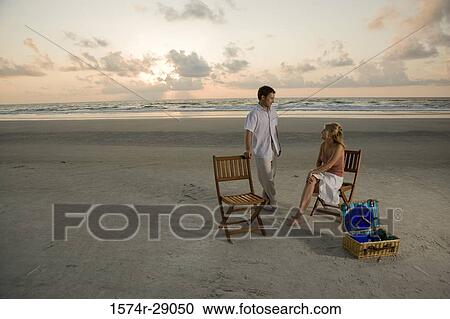 Young couple conversing at the beach View Large Photo Image Stock Image - Young couple conversing at the beach. Fotosearch