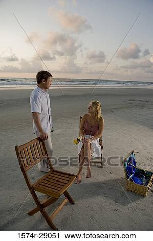 Stock Image - Young couple conversing at the beach. Fotosearch