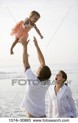 Young couple on the beach with man tossing his daughter View Large Photo Image Stock Image - Young couple on the beach with man tossing his daughter. Fotosearch