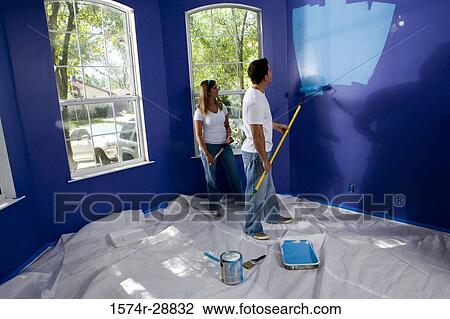 Young couple painting wall with paint roller View Large Photo Image Stock Image - Young couple painting wall with paint roller. Fotosearch