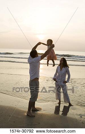Young couple playing with daughter on the beach View Large Photo Image Stock Image - Young couple playing with daughter on the beach. Fotosearch