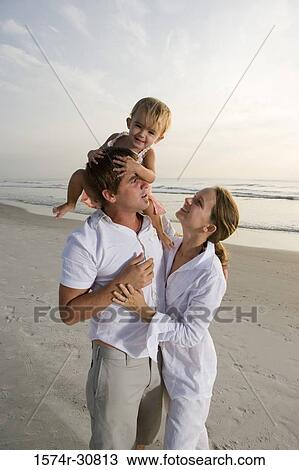 Stock Image - Young couple playing with daughter on the beach. Fotosearch
