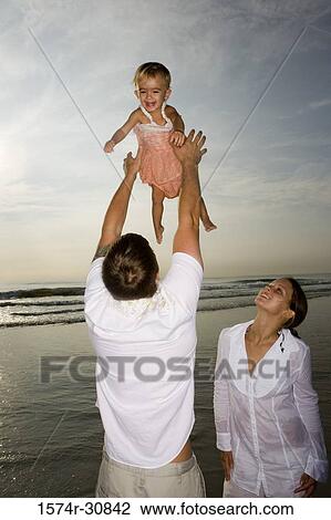 Young couple playing with daughter on the beach View Large Photo Image Stock Image - Young couple playing with daughter on the beach. Fotosearch