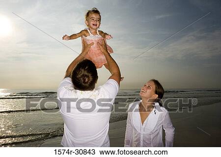 Young couple playing with daughter on the beach View Large Photo Image Stock Image - Young couple playing with daughter on the beach. Fotosearch
