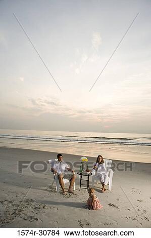 Young couple with daughter relaxing on the beach View Large Photo Image Picture - Young couple with daughter relaxing on the beach. Fotosearch
