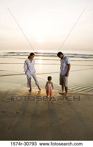 Stock Image - Young couple with daughter relaxing on the beach. Fotosearch