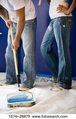 Young couple with paint roller and paint tray standing on drop cloth View Large Photo Image Stock Photo - Young couple with paint roller and paint tray standing on drop cloth. Fotosearch