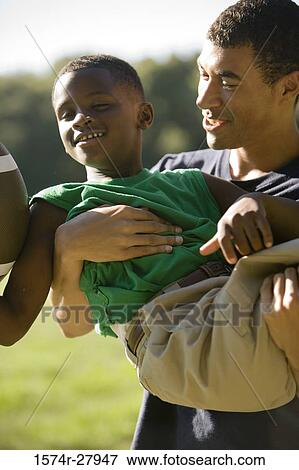 Young man and boy playing with football View Large Photo Image Stock Photo - Young man and boy playing with football. Fotosearch