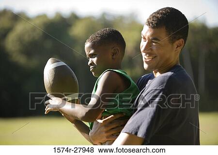 Young man and boy playing with football View Large Photo Image Stock Photo - Young man and boy playing with football. Fotosearch