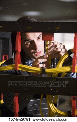 Stock Image - Young man connecting network connection plug. Fotosearch