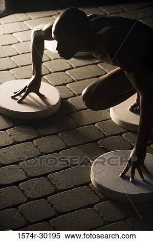Young man crouching on the round tiles View Large Photo Image Stock Photography - Young man crouching on the round tiles. Fotosearch