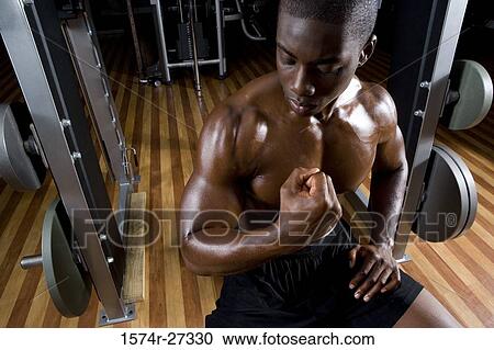 Young man flexing muscles in the gym View Large Photo Image Stock Image - Young man flexing muscles in the gym. Fotosearch