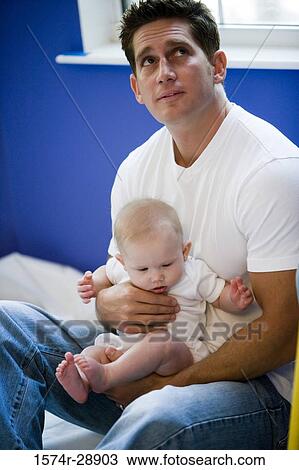 Young man holding baby and looking up View Large Photo Image Stock Image - Young man holding baby and looking up. Fotosearch