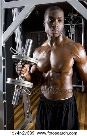 Young man holding dumbbell in the gym View Large Photo Image Stock Photo - Young man holding dumbbell in the gym. Fotosearch