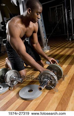 Young man holding dumbbells in the gym View Large Photo Image Stock Photo - Young man holding dumbbells in the gym. Fotosearch