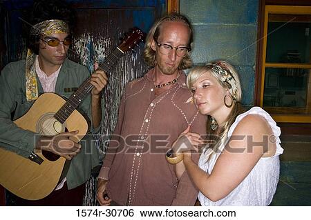 Stock Photograph - Young man holding guitar with parents beside. Fotosearch