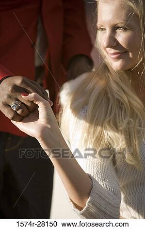 Young man holding hand of a mid adult woman View Large Photo Image Stock Image - Young man holding hand of a mid adult woman. Fotosearch
