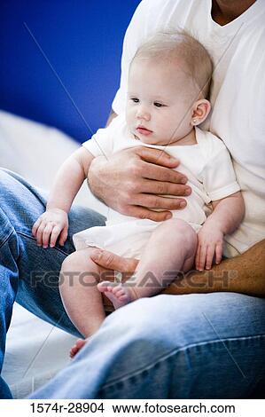 Young man holding his baby on lap View Large Photo Image Picture - Young man holding his baby on lap. Fotosearch