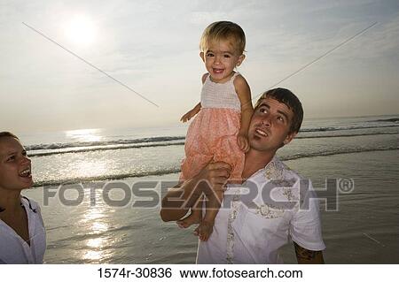Young man holding his daughter on the beach View Large Photo Image Stock Photograph - Young man holding his daughter on the beach. Fotosearch