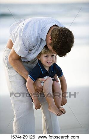 Young man holding son at the beach View Large Photo Image Stock Photography - Young man holding son at the beach. Fotosearch