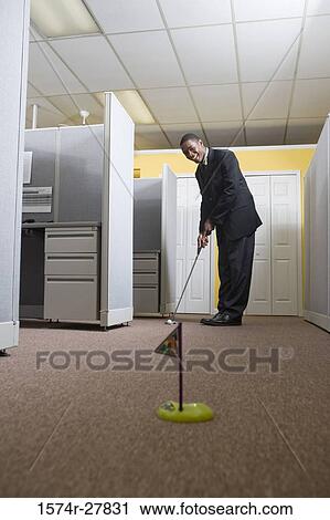 Young man in full suit playing golf in an office View Large Photo Image Stock Image - Young man in full suit playing golf in an office. Fotosearch