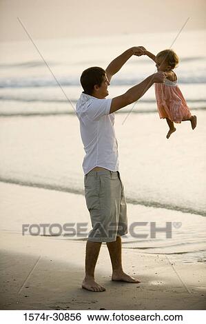Young man lifting his daughter on the beach View Large Photo Image Stock Photograph - Young man lifting his daughter on the beach. Fotosearch