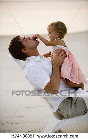 Stock Image - Young man playing with daughter on the beach. Fotosearch