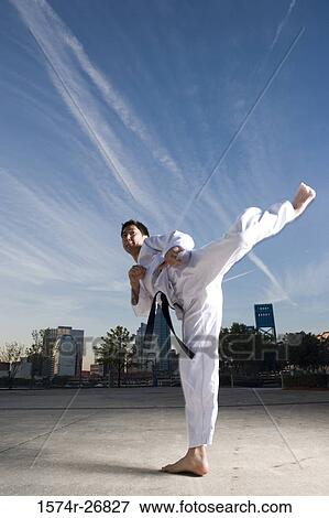 Stock Photo - Young man practicing martial arts in sports uniform on the road. Fotosearch