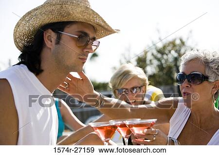 Young man serving drinks to senior women View Large Photo Image Stock Photo - Young man serving drinks to senior women. Fotosearch