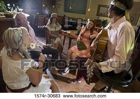 Young man sitting with a guitar while others behind View Large Photo Image Stock Image - Young man sitting with a guitar while others behind. Fotosearch