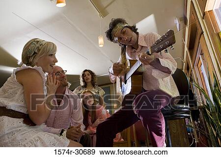 Young man sitting with a guitar while others beside View Large Photo Image Stock Photo - Young man sitting with a guitar while others beside. Fotosearch