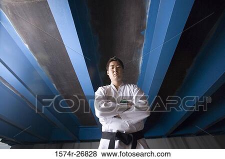Stock Photo - Young man standing in sports uniform with arms crossed. Fotosearch